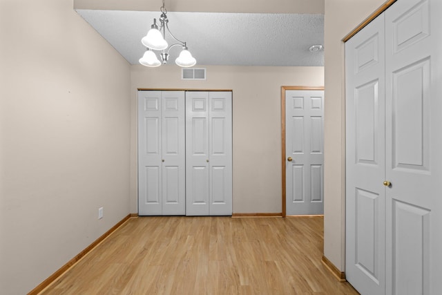 20354 Kensfield Trl Unit 1403, Lakeville, MN 55044 - unfurnished bedroom featuring light wood-type flooring, a chandelier, a textured ceiling, and a closet