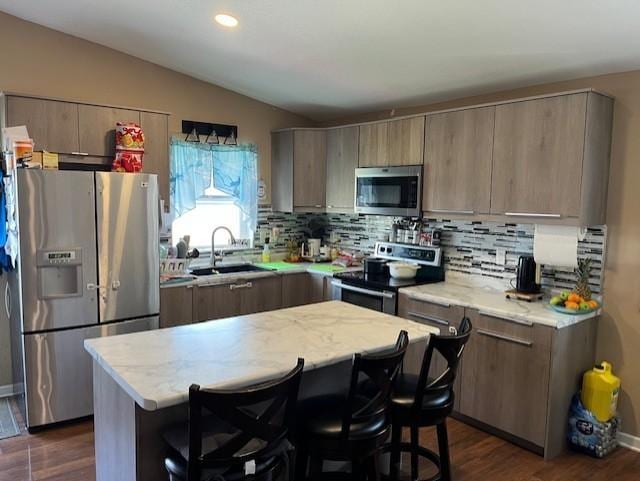 905 Main St, Marshall, MN 56258 - kitchen with stainless steel appliances, vaulted ceiling, backsplash, a kitchen breakfast bar, and dark wood finished floors