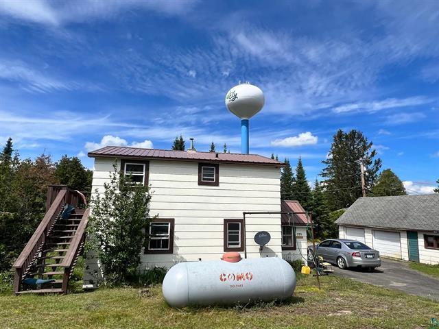 355 Harvey St, Ely, MN 55731 - view of property exterior with a garage, stairs, a metal roof, and a yard