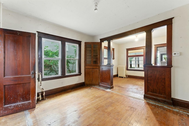 976 Forest St, Saint Paul, MN 55106 - foyer featuring radiator heating unit, light wood-type flooring, and decorative columns