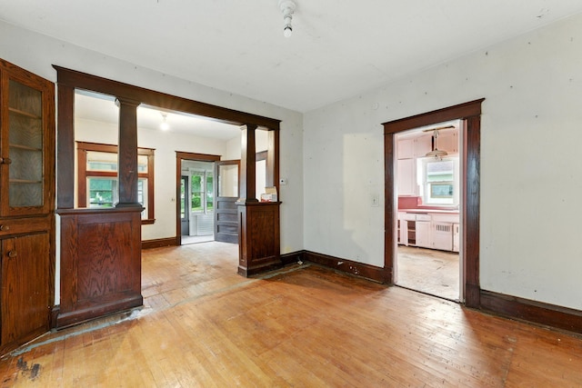 976 Forest St, Saint Paul, MN 55106 - spare room featuring ornate columns, light wood-style flooring, and radiator heating unit