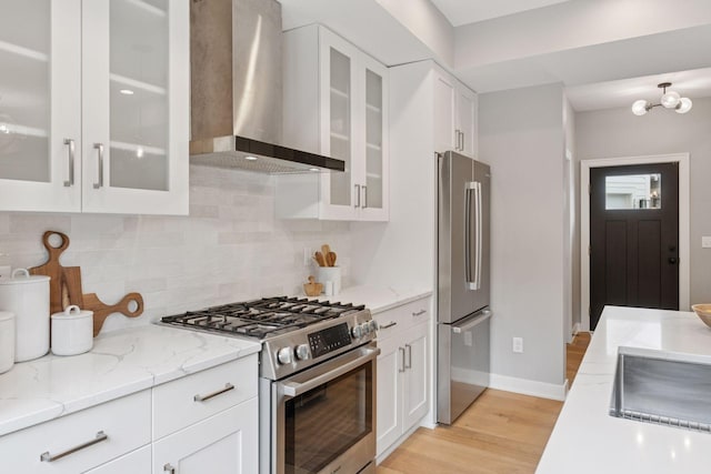 2820 Saint Louis Ave, Minneapolis, MN 55416 - kitchen with wall chimney range hood, stainless steel appliances, tasteful backsplash, white cabinets, and light wood-type flooring