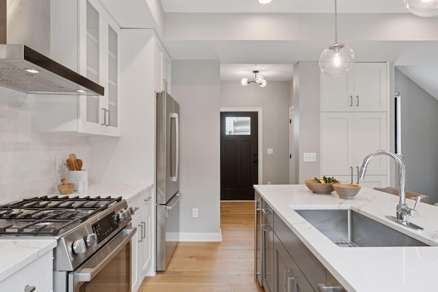 2820 Saint Louis Ave, Minneapolis, MN 55416 - kitchen with wall chimney range hood, appliances with stainless steel finishes, light wood-style floors, tasteful backsplash, and glass insert cabinets