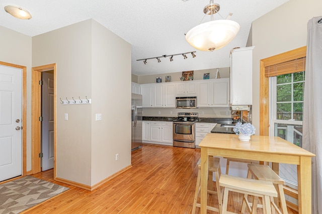 15265 Dupont Path, Apple Valley, MN 55124 - kitchen featuring appliances with stainless steel finishes, white cabinetry, light wood-type flooring, hanging light fixtures, and dark countertops