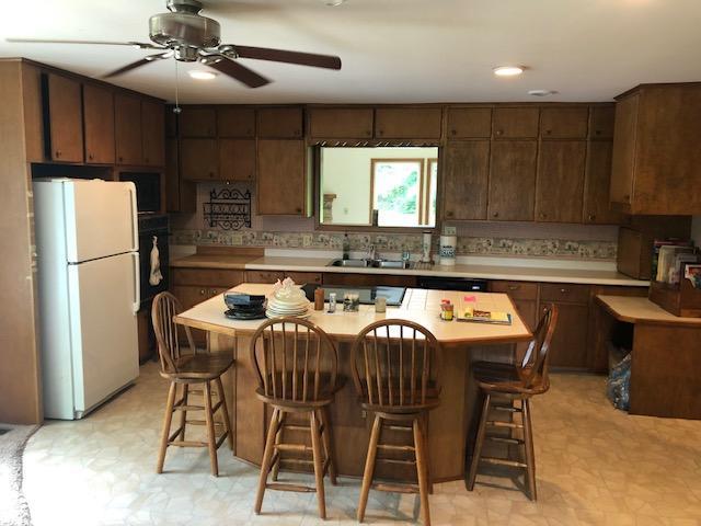 300 Whittier St W, Lanesboro, MN 55949 - kitchen with freestanding refrigerator, light flooring, light countertops, a ceiling fan, and a breakfast bar area