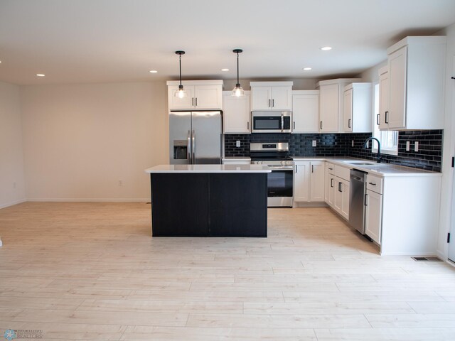7901 Lost River Rd, Horace, ND 58047 - kitchen with stainless steel appliances, decorative backsplash, a kitchen island, light wood-type flooring, and white cabinets