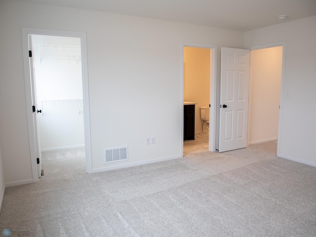 7901 Lost River Rd, Horace, ND 58047 - unfurnished bedroom featuring a spacious closet, light colored carpet, ensuite bath, and a closet