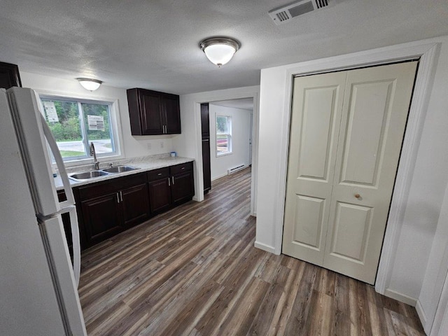 10091 Trengove Rd NW, Bemidji, MN 56601 - kitchen featuring freestanding refrigerator, dark wood-type flooring, light countertops, dark brown cabinets, and a textured ceiling