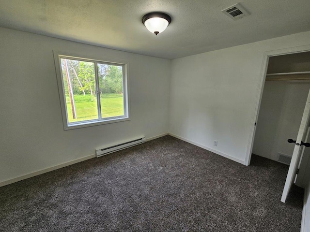 10091 Trengove Rd NW, Bemidji, MN 56601 - unfurnished bedroom featuring a baseboard heating unit, dark carpet, and a closet