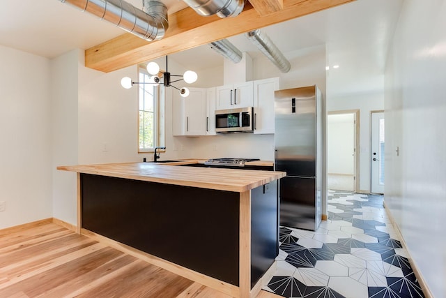 3909 Xerxes Ave S, Minneapolis, MN 55410 - kitchen with butcher block counters, stainless steel appliances, white cabinets, pendant lighting, and a chandelier