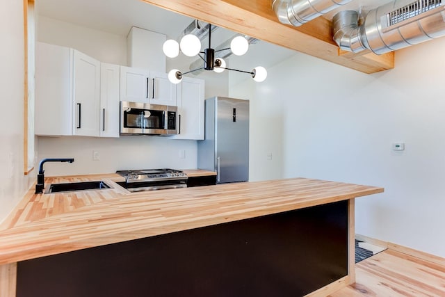 3909 Xerxes Ave S, Minneapolis, MN 55410 - kitchen with appliances with stainless steel finishes, butcher block countertops, a peninsula, wood finished floors, and white cabinets