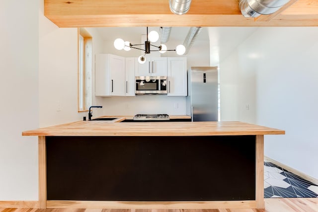 3909 Xerxes Ave S, Minneapolis, MN 55410 - kitchen with stainless steel appliances, butcher block countertops, a peninsula, white cabinets, and a chandelier