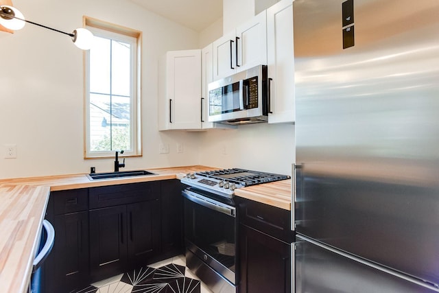 3909 Xerxes Ave S, Minneapolis, MN 55410 - kitchen featuring stainless steel appliances, butcher block counters, dark cabinets, white cabinets, and tile patterned floors