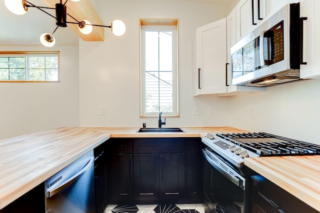 3909 Xerxes Ave S, Minneapolis, MN 55410 - kitchen with appliances with stainless steel finishes, dark cabinetry, a chandelier, wooden counters, and white cabinets