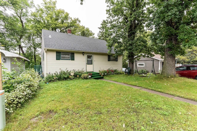 505 1st Ave SE, Pelican Rapids, MN 56572 - view of front facade featuring a front yard, a chimney, roof with shingles, and an outdoor structure
