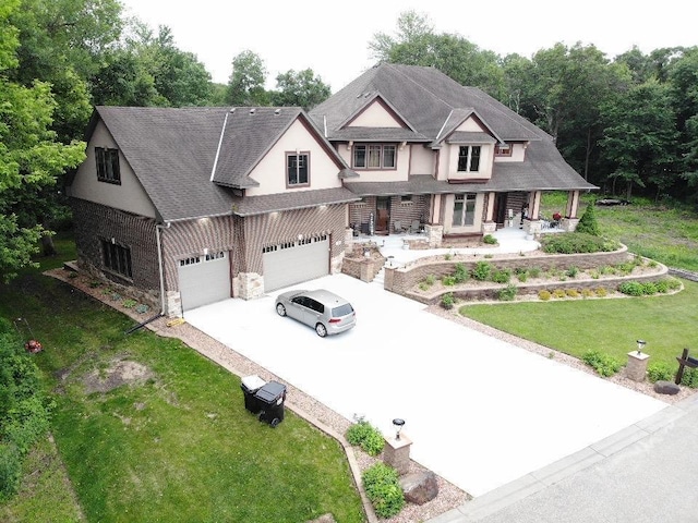 716 169th Ln NE, Ham Lake, MN 55304 - view of front of house featuring concrete driveway, a porch, a front lawn, and stone siding