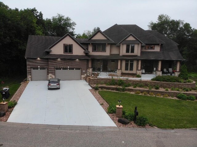 716 169th Ln NE, Ham Lake, MN 55304 - craftsman inspired home featuring a porch, a front yard, concrete driveway, and stone siding