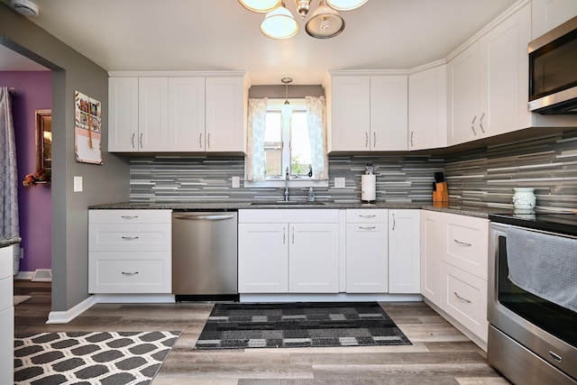 231 Mark St, Winona, MN 55987 - kitchen with stainless steel appliances, a chandelier, light wood finished floors, and white cabinetry