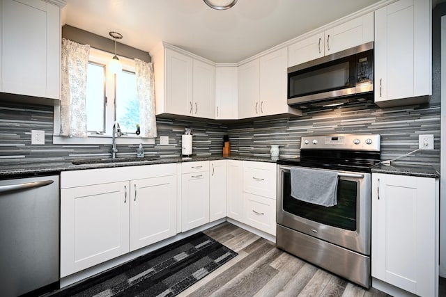 231 Mark St, Winona, MN 55987 - kitchen featuring appliances with stainless steel finishes, tasteful backsplash, white cabinetry, and wood finished floors