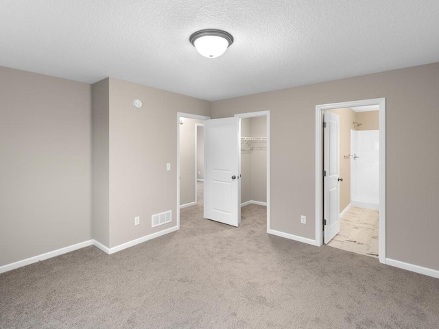 9773 32nd St NE, Saint Michael, MN 55376 - unfurnished bedroom featuring carpet flooring, a textured ceiling, a walk in closet, a closet, and connected bathroom