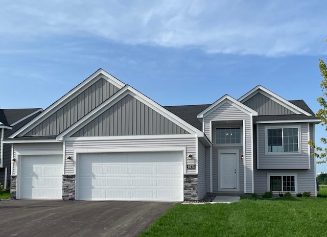 9773 32nd St NE, Saint Michael, MN 55376 - view of front of house featuring board and batten siding, a garage, stone siding, and driveway