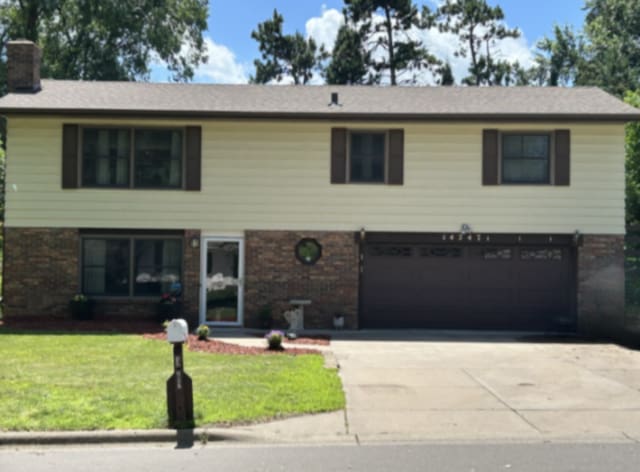 14247 57th St N, Stillwater, MN 55082 - view of front of home featuring concrete driveway, a garage, a front yard, and brick siding