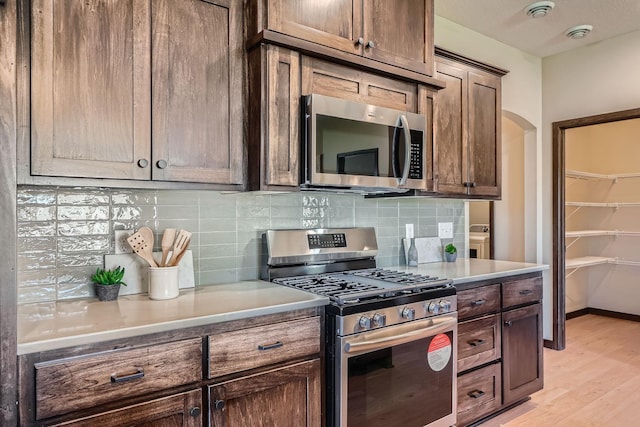 3483 Kady Ave NE, Saint Michael, MN 55376 - kitchen with stainless steel appliances, tasteful backsplash, light wood-type flooring, light countertops, and arched walkways