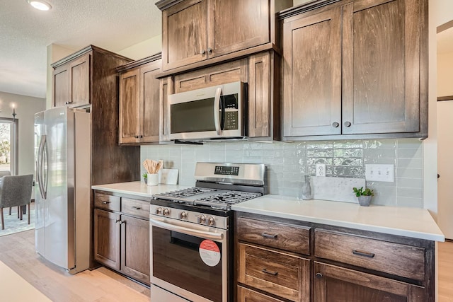 3483 Kady Ave NE, Saint Michael, MN 55376 - kitchen featuring appliances with stainless steel finishes, light wood-style floors, backsplash, light countertops, and a textured ceiling