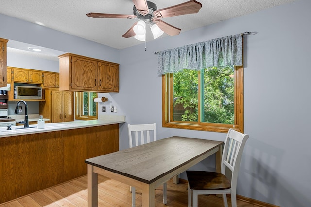 505 Brookview Ln SW, Isanti, MN 55040 - kitchen with stainless steel microwave, brown cabinetry, light wood-style floors, light countertops, and a textured ceiling