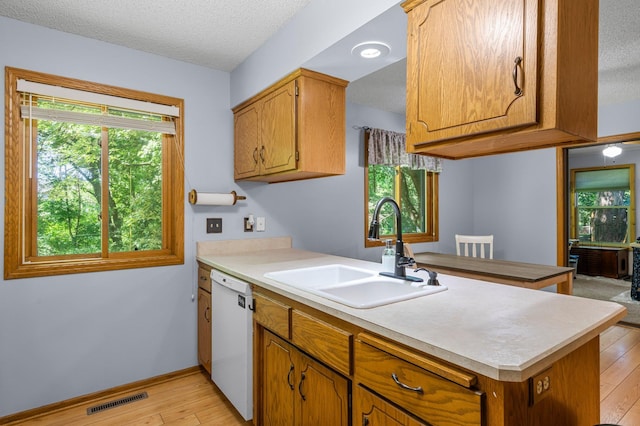 505 Brookview Ln SW, Isanti, MN 55040 - kitchen featuring white dishwasher, light wood-type flooring, light countertops, a peninsula, and brown cabinetry