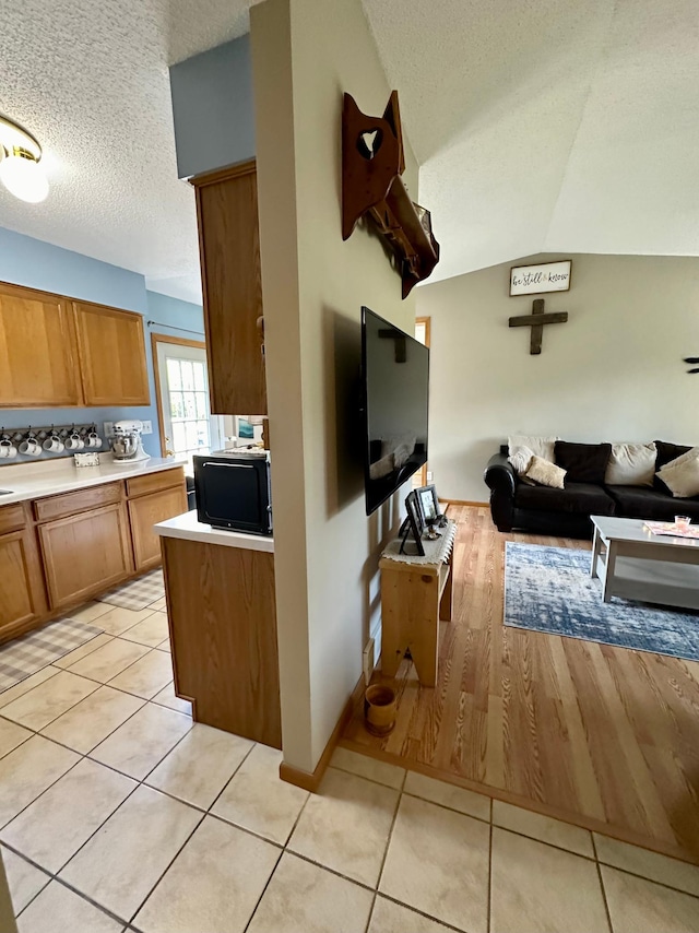 5735 County Road 1, Littlefork, MN 56653 - kitchen with brown cabinets, a textured ceiling, open floor plan, light countertops, and light tile patterned floors