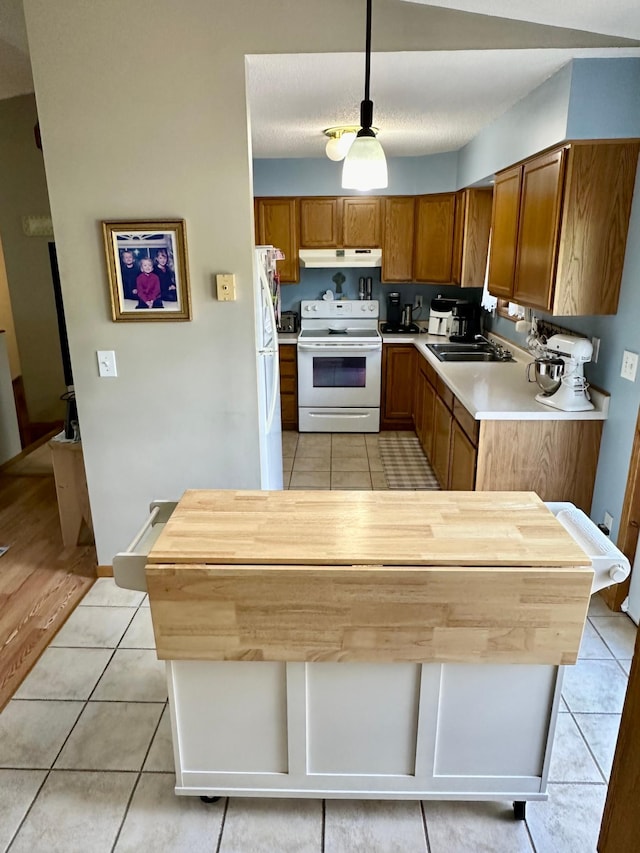 5735 County Road 1, Littlefork, MN 56653 - kitchen featuring white appliances, under cabinet range hood, light tile patterned flooring, brown cabinets, and light countertops