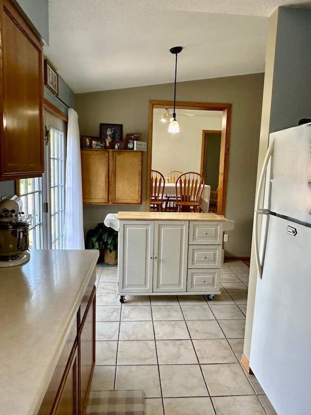 5735 County Road 1, Littlefork, MN 56653 - kitchen featuring freestanding refrigerator, light countertops, hanging light fixtures, light tile patterned floors, and brown cabinetry