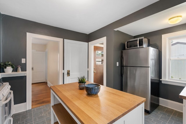 1067 Van Buren Ave, Saint Paul, MN 55104 - kitchen featuring stainless steel appliances, wood counters, healthy amount of natural light, and white cabinets