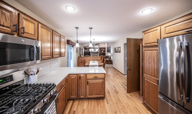 452 Spruce St, Shakopee, MN 55379 - kitchen with appliances with stainless steel finishes, light wood-type flooring, a peninsula, decorative backsplash, and decorative light fixtures