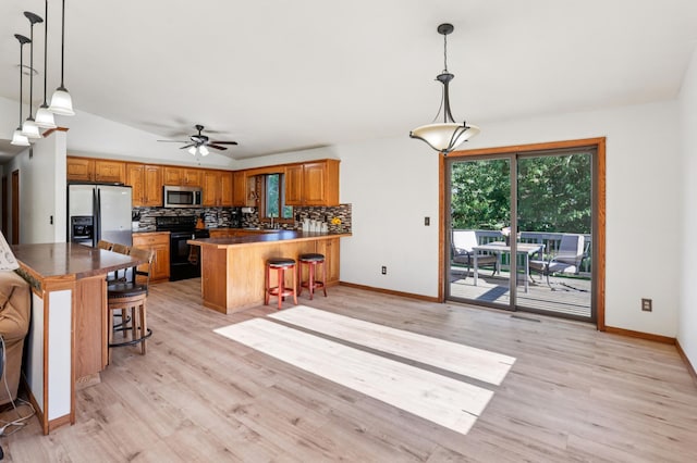 733 Meadow Dr, Hudson, WI 54016 - kitchen featuring appliances with stainless steel finishes, brown cabinetry, a peninsula, tasteful backsplash, and dark countertops