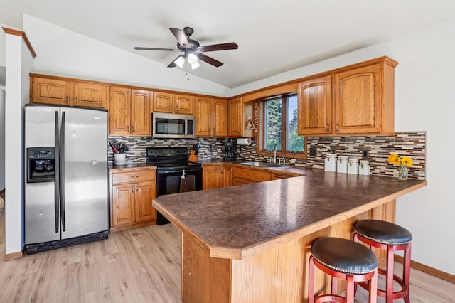 733 Meadow Dr, Hudson, WI 54016 - kitchen featuring appliances with stainless steel finishes, vaulted ceiling, brown cabinetry, a peninsula, and dark countertops