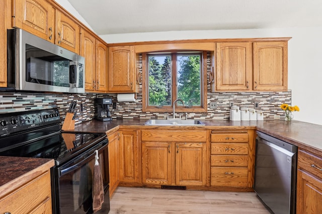 733 Meadow Dr, Hudson, WI 54016 - kitchen with appliances with stainless steel finishes, decorative backsplash, dark countertops, brown cabinetry, and light wood finished floors