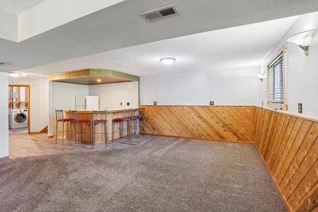 733 Meadow Dr, Hudson, WI 54016 - indoor bar featuring washer / clothes dryer, freestanding refrigerator, carpet flooring, wood walls, and a wainscoted wall