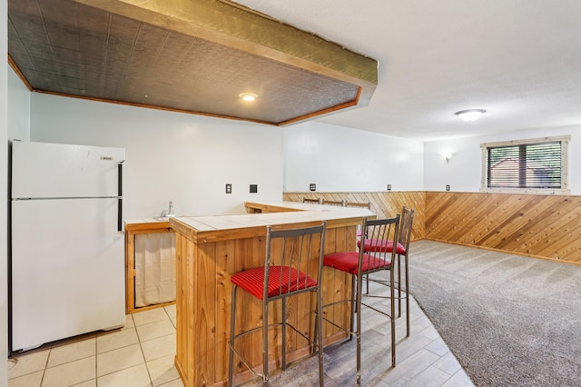 733 Meadow Dr, Hudson, WI 54016 - kitchen with freestanding refrigerator, tile counters, wooden walls, a wainscoted wall, and a breakfast bar
