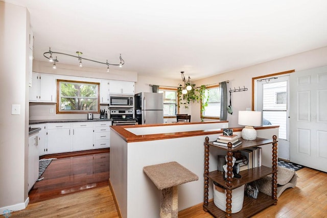 1124 15th St N, Moorhead, MN 56560 - kitchen featuring stainless steel appliances, white cabinets, light wood finished floors, and a kitchen island