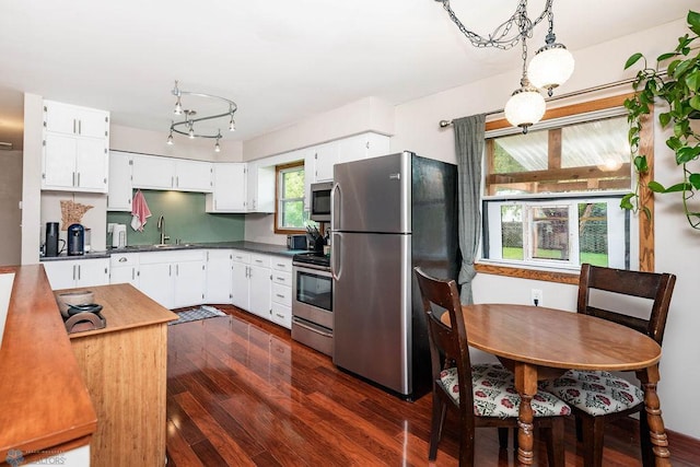 1124 15th St N, Moorhead, MN 56560 - kitchen featuring stainless steel appliances, dark countertops, dark wood finished floors, and white cabinets