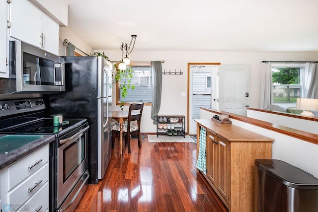 1124 15th St N, Moorhead, MN 56560 - kitchen featuring appliances with stainless steel finishes, dark wood-type flooring, white cabinetry, and decorative light fixtures