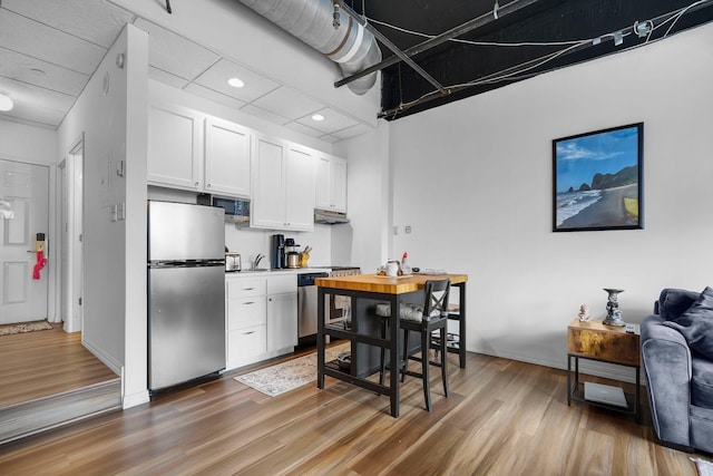 431 7th St Unit 2605, Minneapolis, MN 55415 - kitchen with stainless steel appliances, light wood finished floors, white cabinetry, recessed lighting, and under cabinet range hood