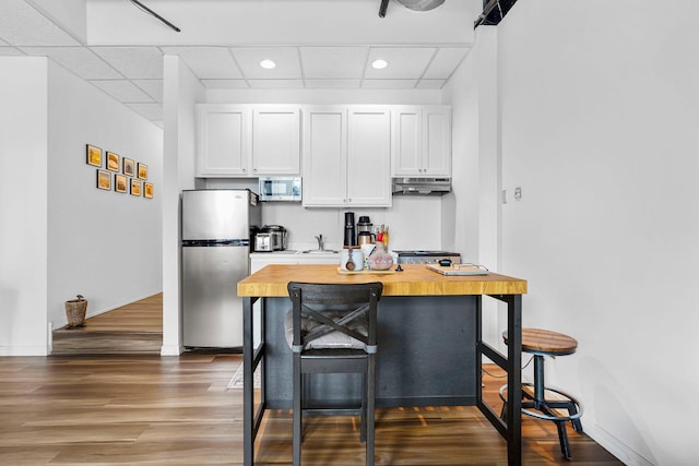 431 7th St Unit 2605, Minneapolis, MN 55415 - kitchen featuring stainless steel appliances, wood finished floors, under cabinet range hood, white cabinets, and recessed lighting