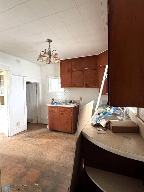 310 1st St SW, Mahnomen, MN 56557 - kitchen featuring brown cabinets, a chandelier, light countertops, and hanging light fixtures