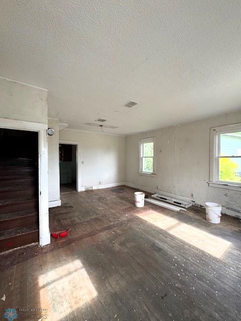 310 1st St SW, Mahnomen, MN 56557 - unfurnished living room with wood finished floors, a textured ceiling, and a baseboard heating unit