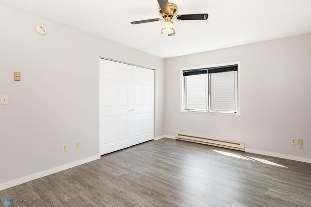 3050 18th St S, Fargo, ND 58103 - unfurnished bedroom with baseboard heating, wood finished floors, a closet, and ceiling fan