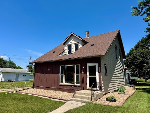 720 Fir Ave, Bird Island, MN 55310 - view of front of home featuring a front lawn, a chimney, a shingled roof, and board and batten siding