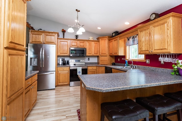 106 12th St NE, Barnesville, MN 56514 - kitchen with appliances with stainless steel finishes, a peninsula, lofted ceiling, a kitchen bar, and light wood finished floors